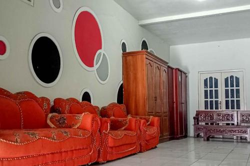 a living room with a red couch against a wall at Arjuna 2 Homestay Syariah Dieng in Dieng