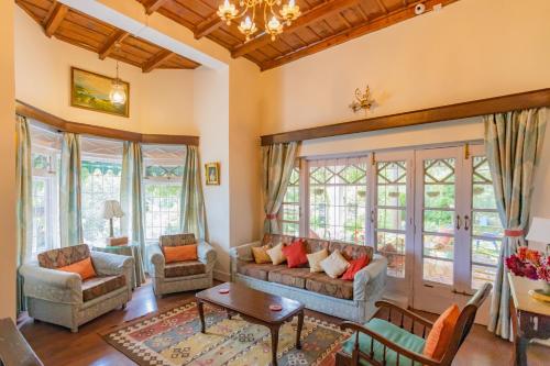 a living room with a couch and chairs and windows at Seclude Ramgarh Taradale in Rāmgarh