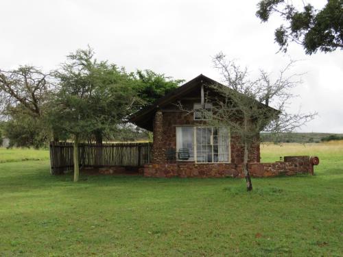 a small brick house in a field with a tree at Bateleur Nature Reserve in Modimolle