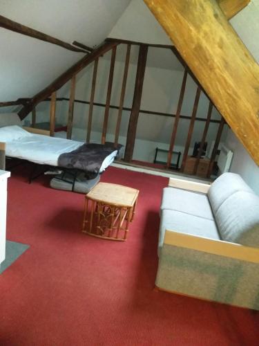 Cette chambre mansardée comprend deux lits et un canapé. dans l'établissement LOGIS Hôtel - Les Paturelles, à Avesnelles