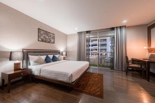 a bedroom with a bed and a desk and a window at Grand Asoke Suites Boutique Residence in Bangkok