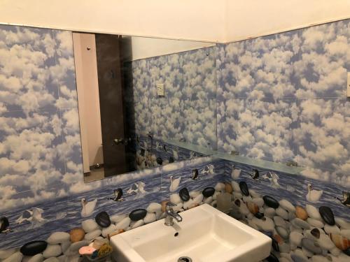 ein Badezimmer mit einem Waschbecken und einem Spiegel mit Wolken an der Wand in der Unterkunft Anniewatte House in Kandy