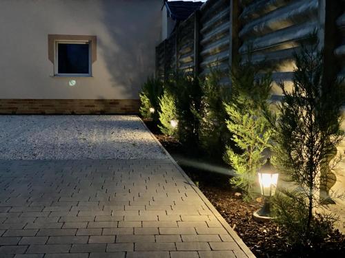 a courtyard with a pathway with lights and a house at Vörösmarty apartmanház in Makó