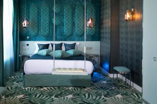 a bedroom with a canopy bed with blue and green walls at Paris j'Adore Hotel & Spa in Paris