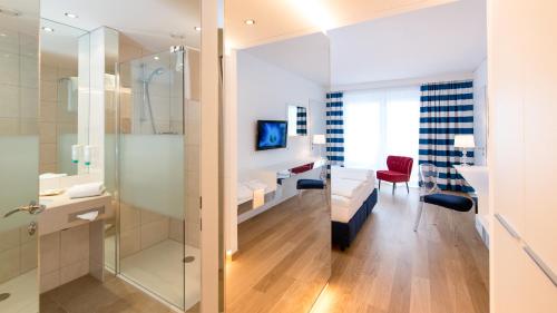 een badkamer met een glazen douche en een slaapkamer bij Werzers Hotel Resort Pörtschach in Pörtschach am Wörthersee
