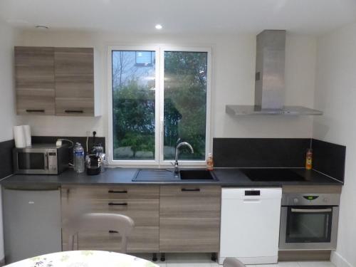 une cuisine avec un évier et une fenêtre dans l'établissement LA MAISON BLEUE, à Arzon