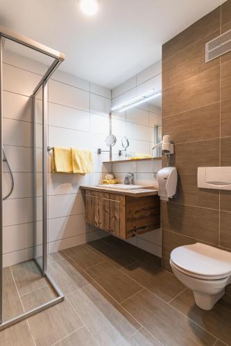 a bathroom with a toilet and a sink and a shower at Hotel Der Schmittenhof in Zell am See