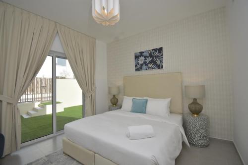 ein Schlafzimmer mit einem weißen Bett und einem großen Fenster in der Unterkunft bnbmehomes - Elegant 3 BR - Dubai South - G04 in Dubai