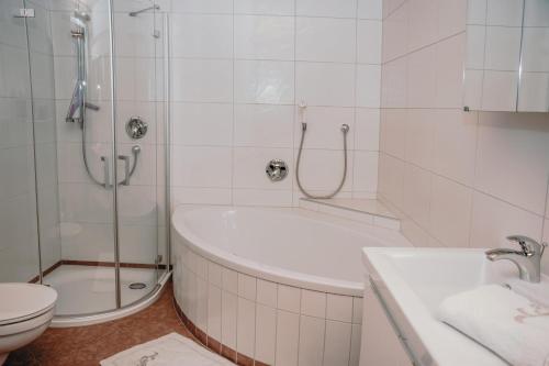 a bathroom with a shower and a tub and a toilet at Haus Gantschnigg in Jochberg