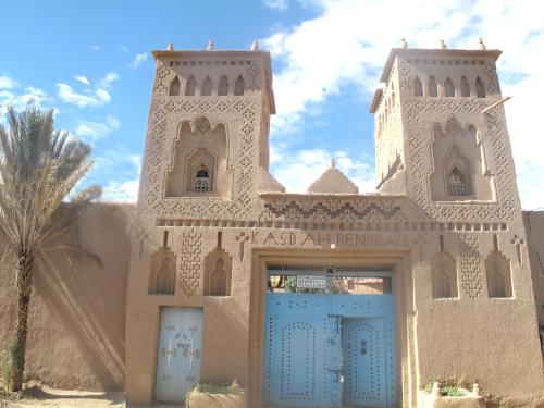 un bâtiment avec deux portes bleues et un palmier dans l'établissement Gite Kasbah La Palmeraie, à Skoura