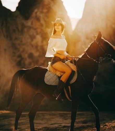 a woman is sitting on a horse at Deep Cave House in Urgup