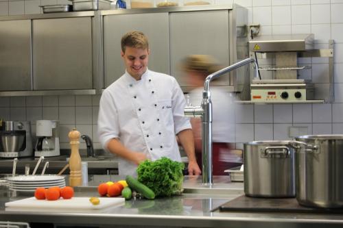 a chef standing in a kitchen preparing food at Landgasthof Ostermair in Petershausen