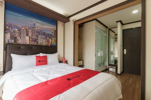 um quarto com uma cama grande e uma pintura na parede em RedDoorz Plus @ Pondok Labu em Jakarta