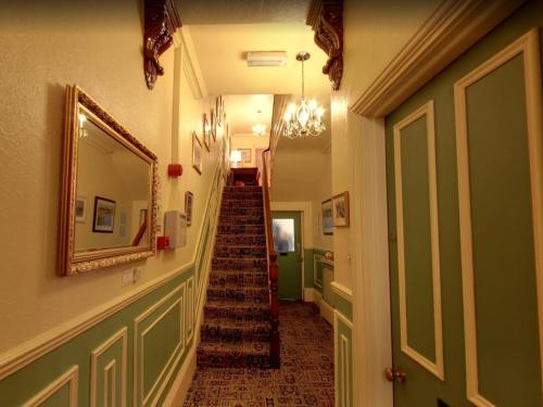 a hallway with a stairway with a mirror and a stair case at Athol House in Filey