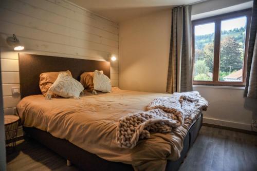a bedroom with a large bed with a large window at Les 2 Clefs in Bussang