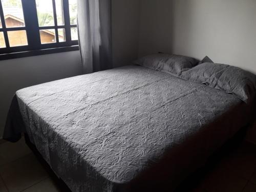 a bed in a small room with a window at LINDO SOBRADO A 250mts DA PRAIA MARISCAL PISCINA 249-3 in Bombinhas