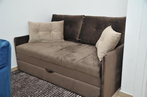 Un sofá de cuero marrón con dos almohadas. en Apartmani Krstojević Kopaonik en Kopaonik