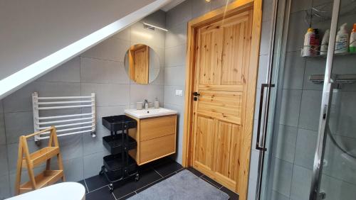 a bathroom with a sink and a wooden door at Załakowo, Na Gwizdówce 11 in Załakowo