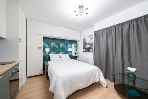 a white bedroom with a bed and a table at Frontière Monaco, Studio rénové - AE in Beausoleil