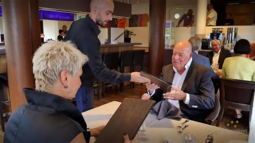 a man handing another man a tablet in a restaurant at Best Western Hotel Slenaken in Slenaken