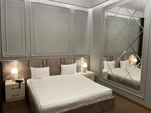a bedroom with a large white bed and a mirror at Paradise Hotel Baku in Baku