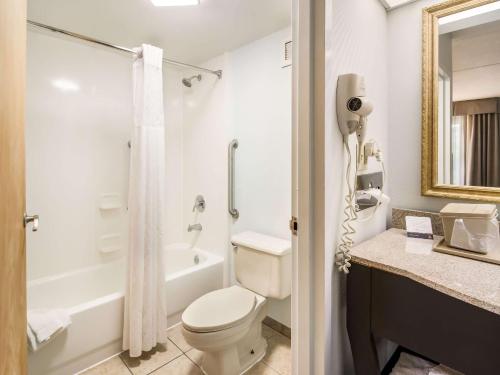 a white bathroom with a toilet and a shower at Clarion Inn Cleveland in Cleveland
