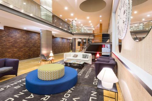 a lobby with a table and chairs and a staircase at Hotel Castellon Center Affiliated by Meliá in Castellón de la Plana