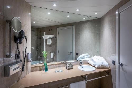 a bathroom with a sink and a large mirror at Hotel Castellon Center Affiliated by Meliá in Castellón de la Plana