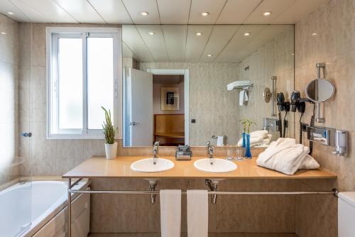 
a bathroom with a sink, mirror, and bath tub at Hotel Castellon Center Affiliated by Meliá in Castellón de la Plana
