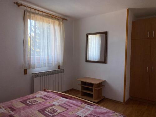 a bedroom with a bed and a table and a window at Apartmani Marija in Jahorina