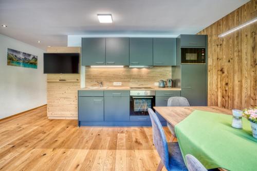 a kitchen with blue cabinets and a wooden floor at HUS23 with Wellness in Schröcken