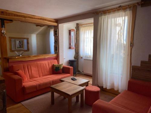 a living room with an orange couch and a table at Apartmani Marija in Jahorina