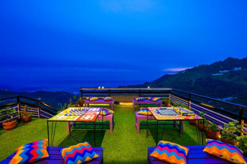 a balcony with tables and chairs on top of a mountain at goSTOPS Mussoorie, Library Road in Mussoorie