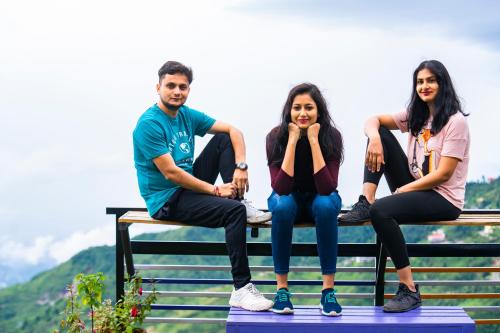 a group of three people sitting on a bench at goSTOPS Mussoorie, Library Road in Mussoorie