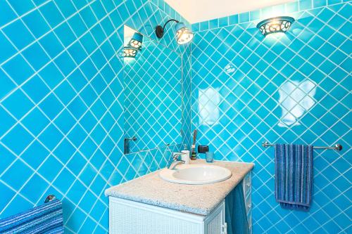 baño con paredes de azulejos azules y lavabo en Casa Isabella villa con dependance, en Porto San Paolo