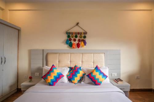 a bedroom with a bed with four colorful pillows at goSTOPS Mussoorie, Library Road in Mussoorie