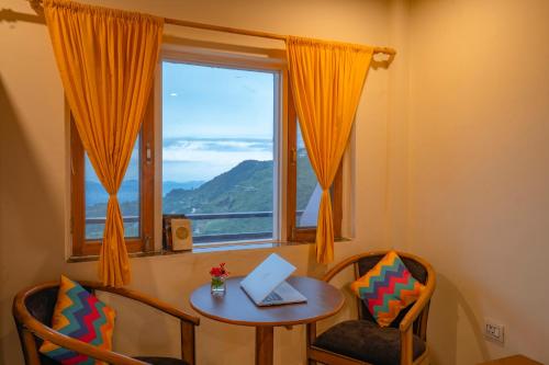 a table with a laptop on it next to a window at goSTOPS Mussoorie, Library Road in Mussoorie