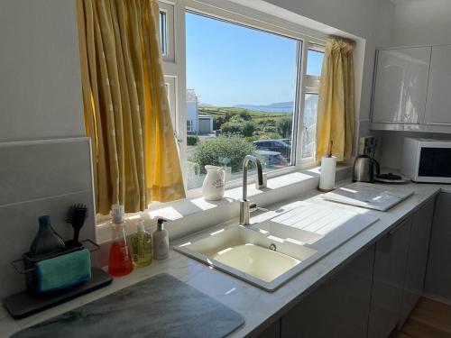 um balcão de cozinha com um lavatório e uma janela em Deu Draeth em Abersoch