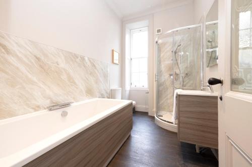 a white bathroom with a tub and a shower at ALTIDO Sophisticated and Bright 4BR apt near Edinburgh Castle in Edinburgh