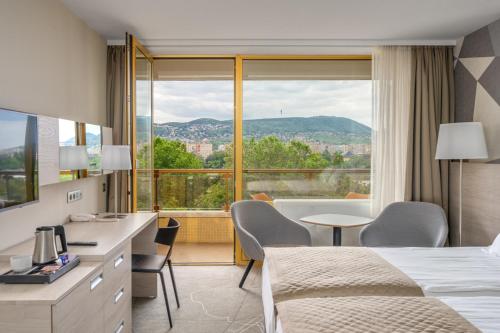 a hotel room with two beds and a large window at Ensana Thermal Margaret Island in Budapest