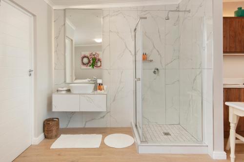a white bathroom with a shower and a sink at 6 Stemmet Lodge in Hermanus