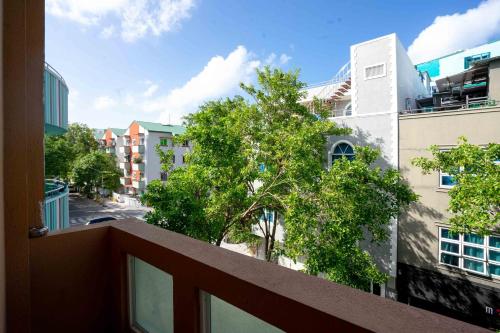 a balcony with a view of a tree and buildings at Noomoo Hulhumale in Hulhumale