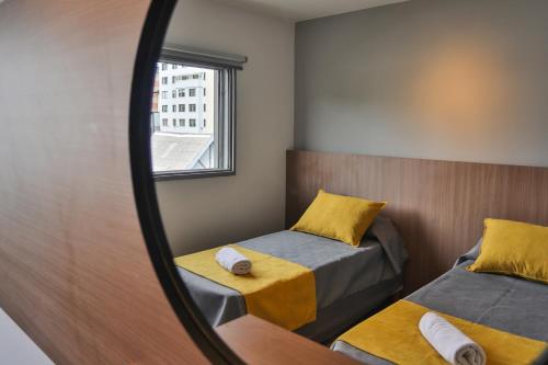 a mirror in a room with two beds and a window at HOTEL CONCEPT BARILOCHE in San Carlos de Bariloche