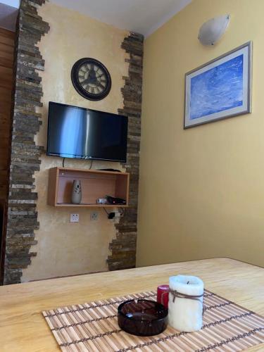 a room with a table and a clock on a wall at Apartmani Marija in Jahorina