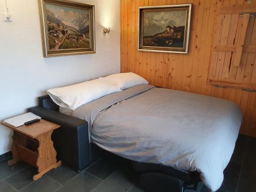 a small bedroom with a bed and a table and two pictures at Premium Jacuzzi Central Verbier Studio, High Floor in Verbier