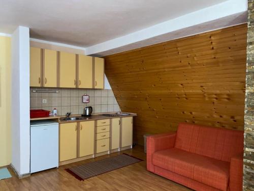 a kitchen with yellow cabinets and a red couch at Apartmani Marija in Jahorina