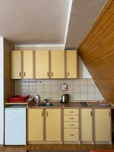a kitchen with yellow cabinets and a white refrigerator at Apartmani Marija in Jahorina