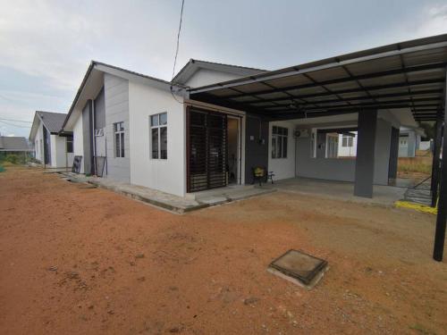 a white house with a dirt yard in front of it at MODERN , SPACIOUS GAMBANG UMP 18 Guest House in Gambang