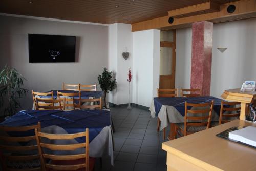 un restaurante con mesas y sillas y TV en la pared en Hotel Garni Pension Ruth en Mutterstadt