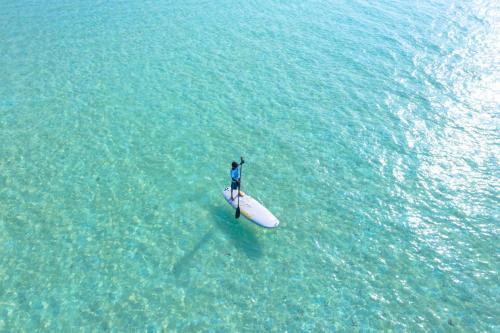 a man standing on a surfboard in the water at Noomoo Hulhumale in Hulhumale